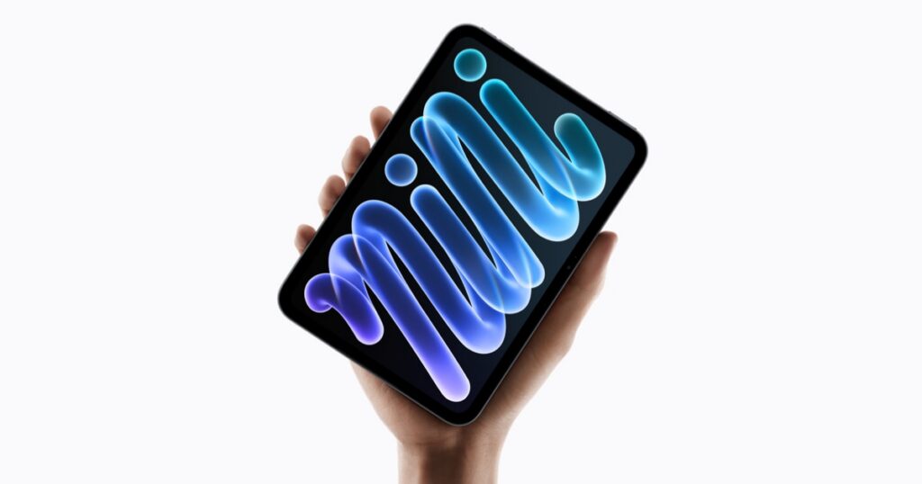 A hand holding the new iPad mini against a white background, its screen showing a glowing blue and purple swirl that spells out the word mini