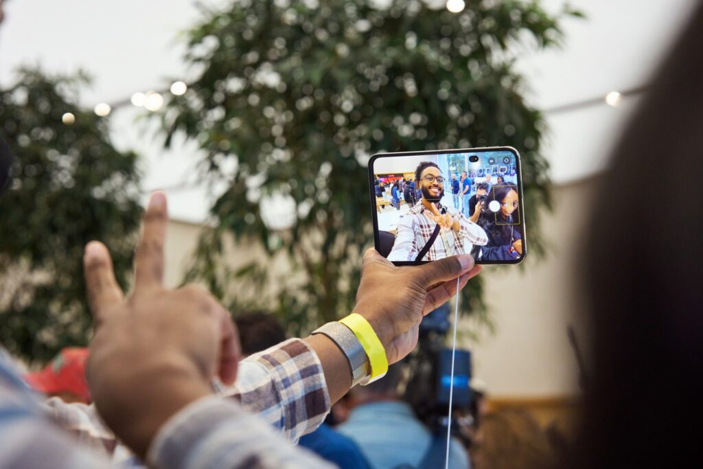 A customer holding up an open iPhone Duo, his face showing on the display that faces the camera