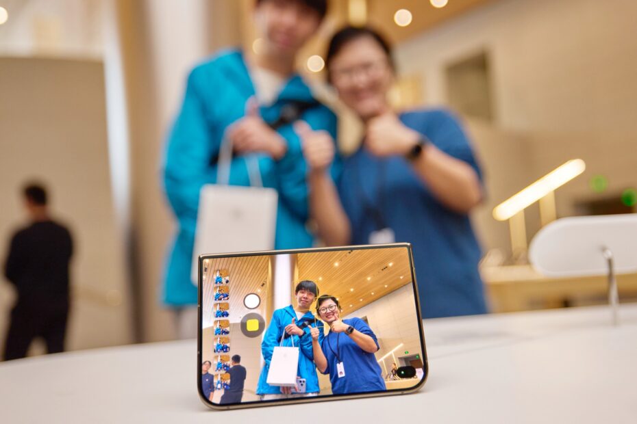 iPhone Duo standing on a table, taking a photo of two people giving a thumbs up