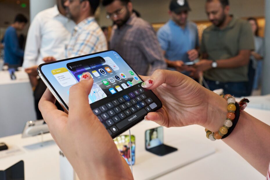 Hands holding iPhone Duo sideways and partly folded, with the keyboard on the lower half